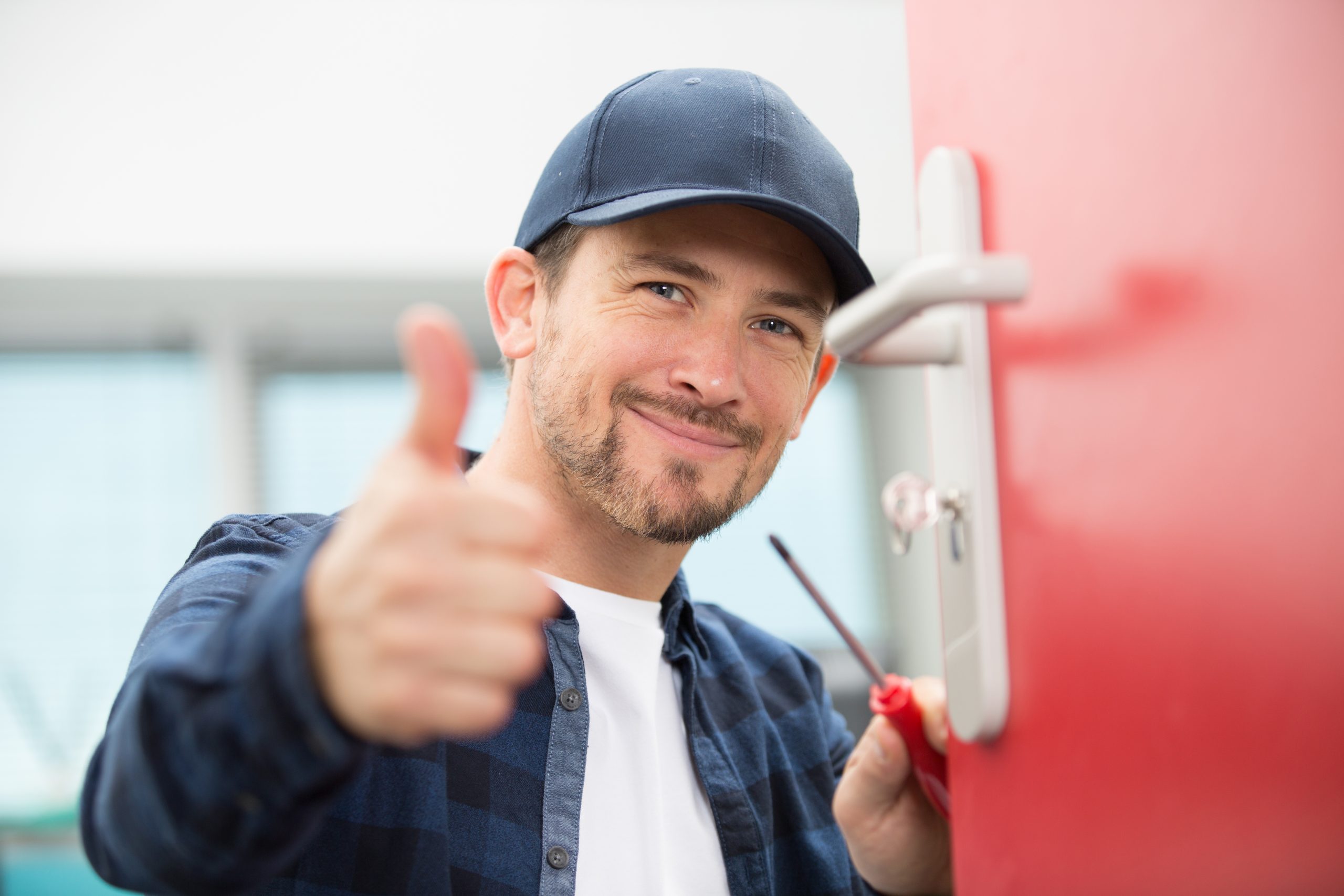 A man fixing a door and giving the thumbs up